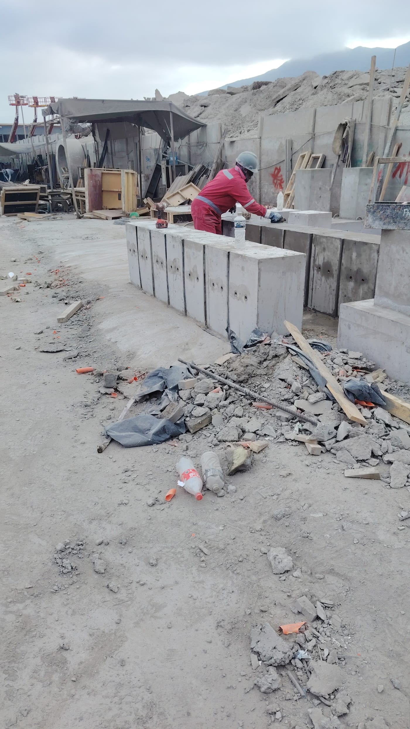 Operario trabajando en piezas prefabricadas de hormigón en patio de fabricación.